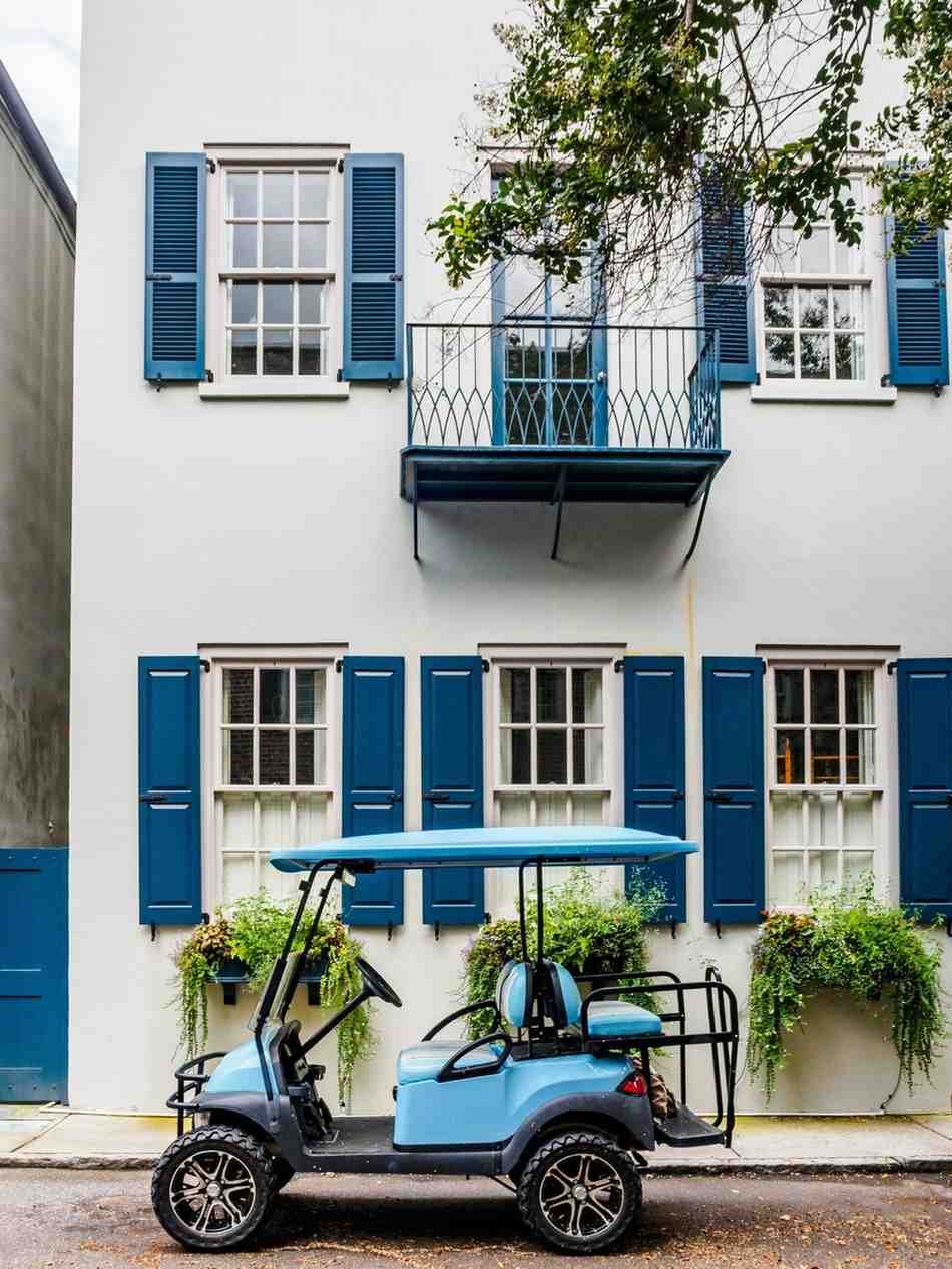 A light blue golf cart is parked on the street in front in Charleston SC