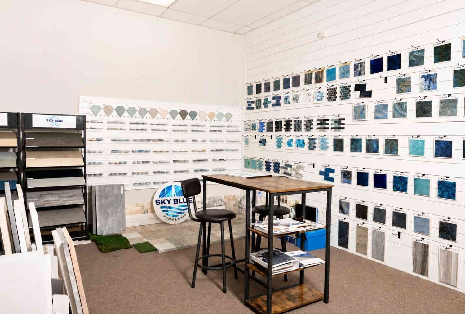 Pool design showroom with tile, coping, and finish samples displayed on walls and racks